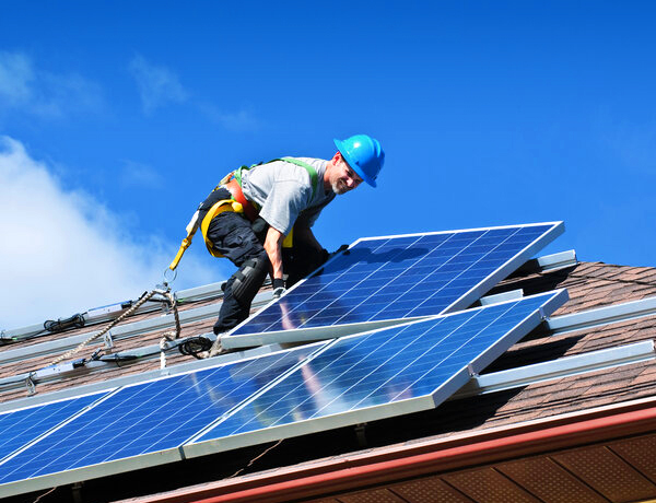 Fachkundiger Handwerker installiert eine Photovoltaikanlage auf einem Hausdach für nachhaltige Stromerzeugung