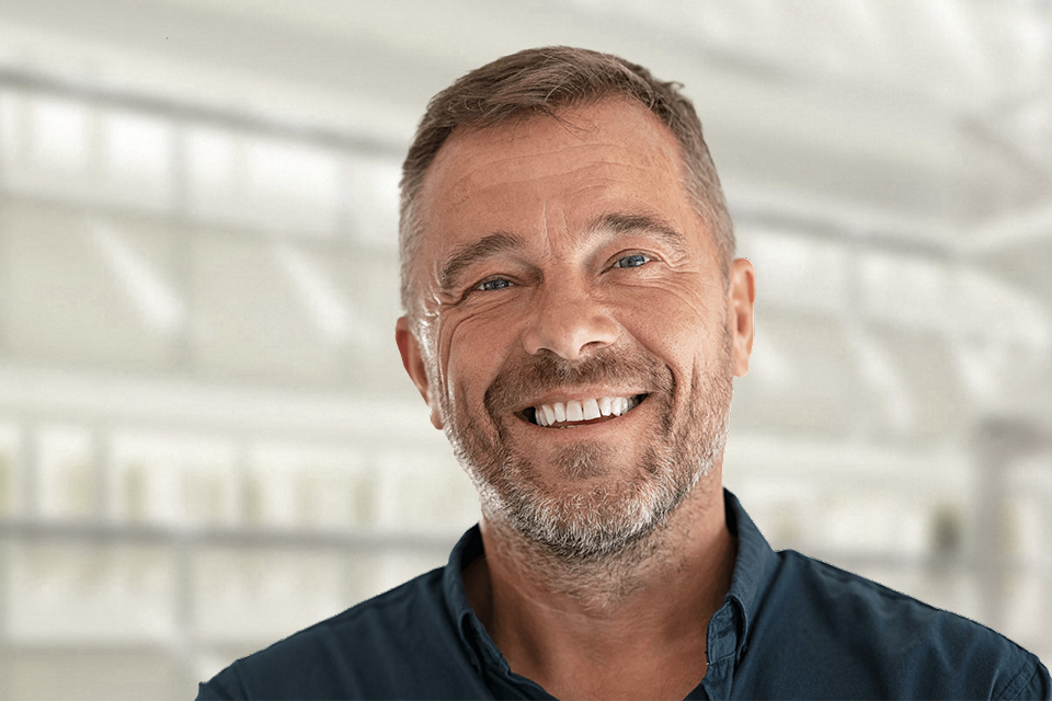 Zufriedener Kunde steht entspannt vor einem Fenster und genießt den Ausblick.